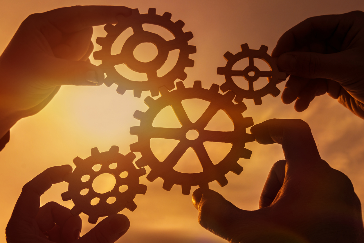 Gears in the hands of people on the background of the evening sky.